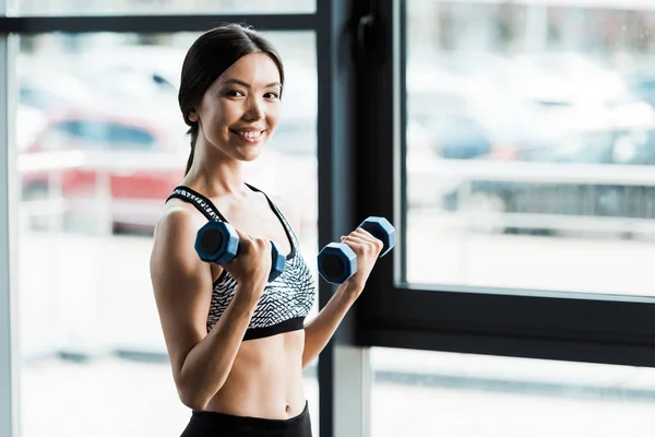 Donna felice che tiene i manubri mentre si allena in palestra — Foto stock