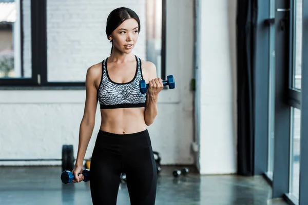 Attractive girl exercising with dumbbells in sports center — Stock Photo
