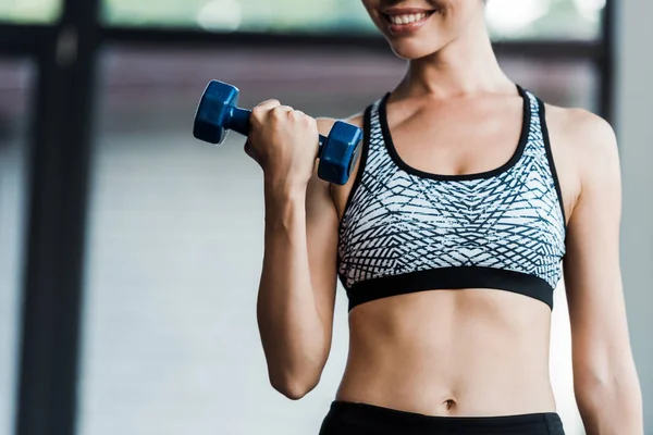 Cropped view of sportswoman holding dumbbell in gym — Stock Photo