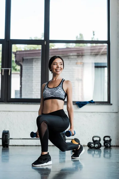 Positive Sportlerin macht Kniebeuge mit Hanteln — Stockfoto