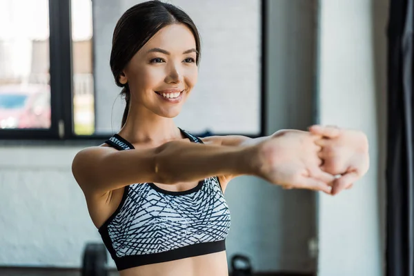 Selective focus of cheerful girl stretching while warming up in gym — Stock Photo