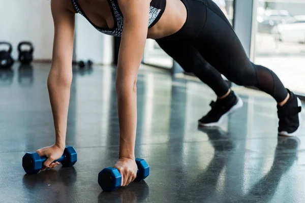 Cropped view of sporty girl exercising with dumbbells in sports center — Stock Photo