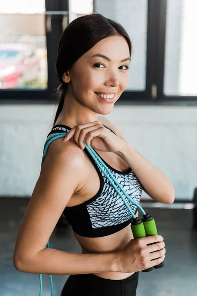 Cheerful young woman holding jumping rope in gym — Stock Photo