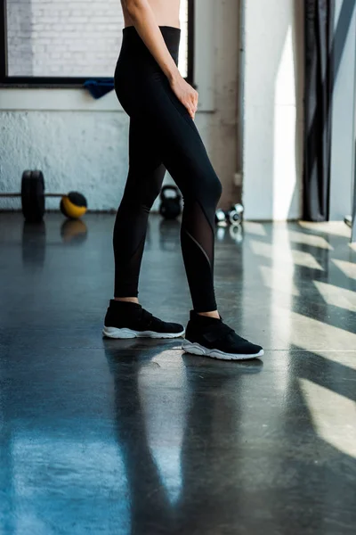 Vista ritagliata della donna atletica in piedi in abbigliamento sportivo in palestra — Stock Photo