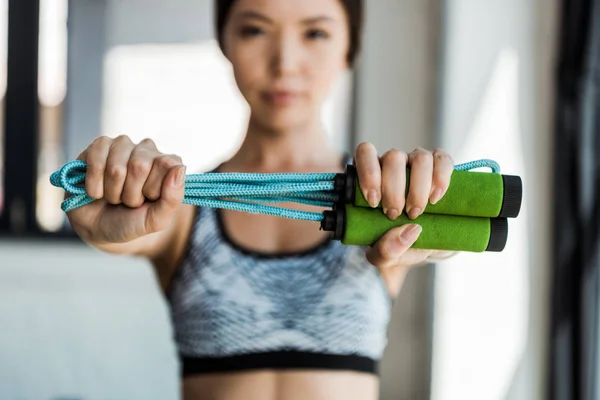 Selective focus of young woman holding skipping rope — Stock Photo