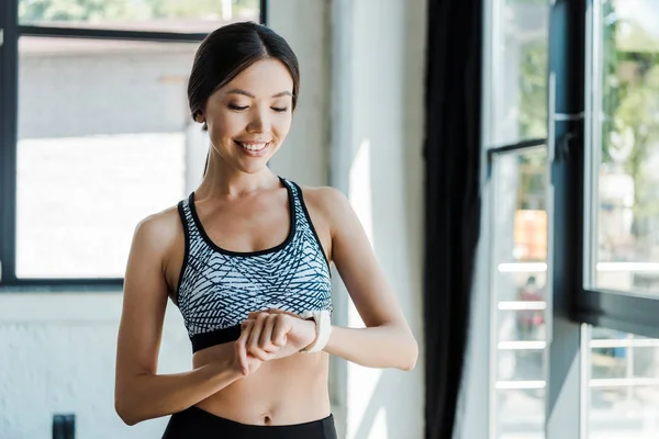 Happy sportswoman looking at fitness watch in sports center — Stock Photo