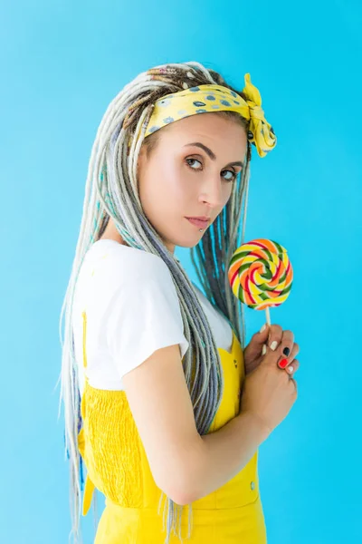 Girl with dreadlocks holding lollipop and looking at camera isolated on turquoise — Stock Photo