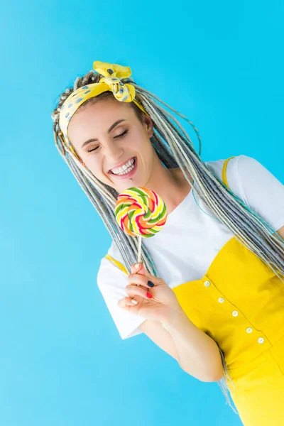 Smiling girl with dreadlocks holding lollipop isolated on turquoise — Stock Photo