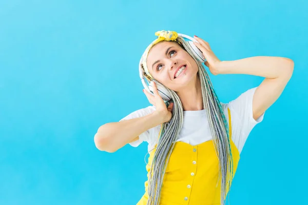 Menina feliz com dreadlocks em fones de ouvido isolados em turquesa — Fotografia de Stock
