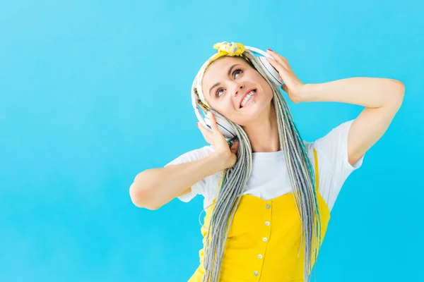 Fille heureuse avec dreadlocks dans casque isolé sur turquoise — Photo de stock