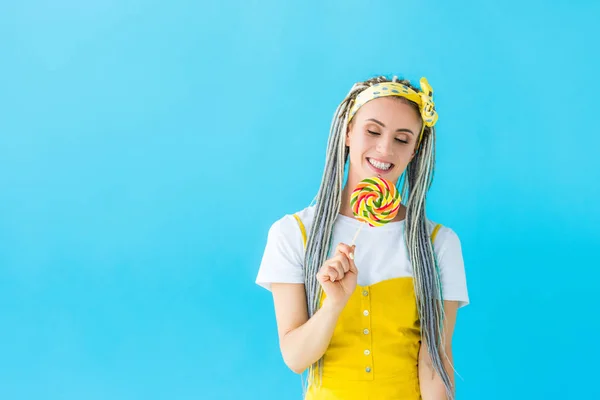 Happy girl with dreadlocks holding lollipop isolated on turquoise with copy space — Stock Photo
