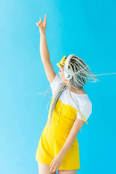 Girl with dreadlocks in headphones showing rock sign on turquoise — Stock Photo