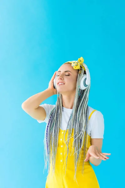 Дівчина з дредлоками в навушниках слухає музику ізольовано на бірюзовому — стокове фото