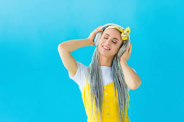 Mädchen mit Dreadlocks in Kopfhörern lächelt vereinzelt auf Türkis — Stockfoto