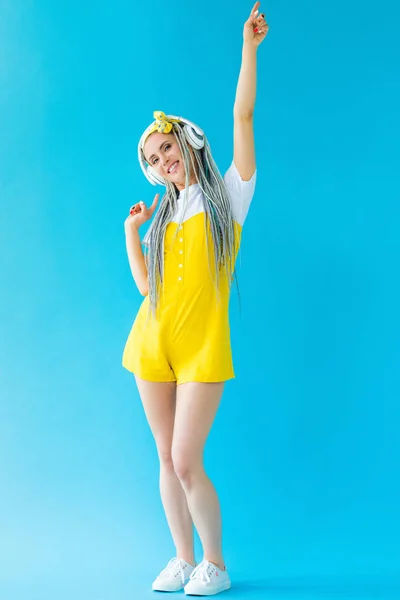 Chica con rastas en auriculares apuntando con los dedos en turquesa - foto de stock