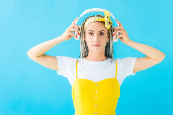 Chica con rastas poner en auriculares aislados en turquesa - foto de stock