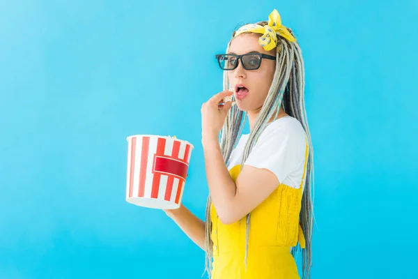 Girl with dreadlocks in 3d glasses eating popcorn isolated on turquoise — Stock Photo