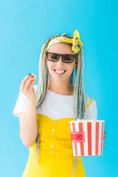 Happy girl with dreadlocks in 3d glasses holding popcorn isolated on turquoise — Stock Photo