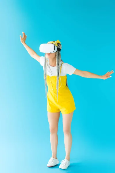 Дівчина з дредлоками у гарнітурі віртуальної реальності жестикулює на бірюзовому — стокове фото