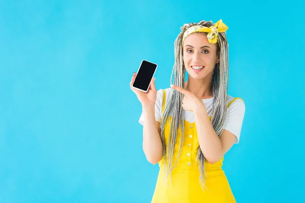 Mädchen mit Dreadlocks zeigt mit dem Finger auf Smartphone mit leerem Bildschirm auf Türkis — Stockfoto