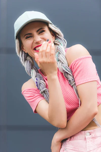 Bela menina elegante com dreadlocks no chapéu rindo e gesticulando com a mão — Fotografia de Stock