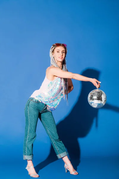 Beautiful stylish girl posing with disco ball on blue — Stock Photo