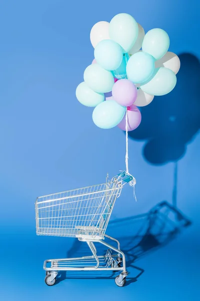Ballons décoratifs attachés au panier vide sur bleu — Photo de stock