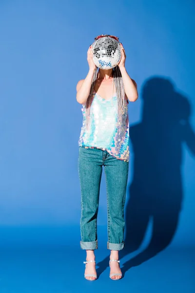 Stylish girl covering face with disco ball on blue — Stock Photo