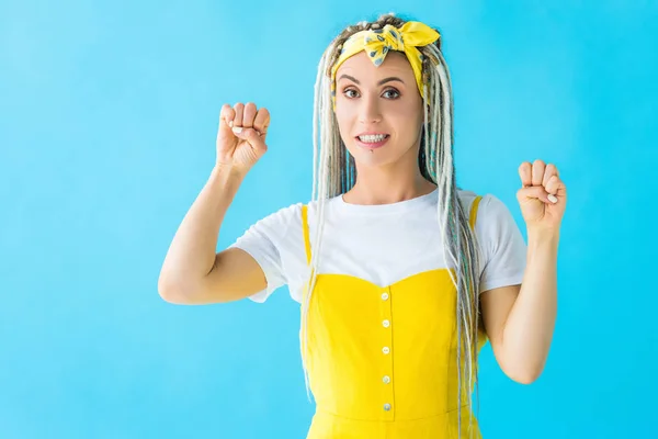 Glückliches Mädchen mit Dreadlocks imitiert Türklopfen mit geballten Fäusten isoliert auf Türkis — Stockfoto