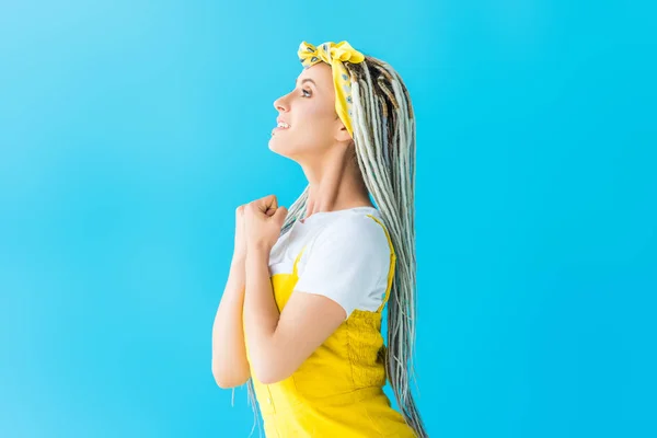 Side view of girl with dreadlocks and clenched fist isolated on turquoise — Stock Photo