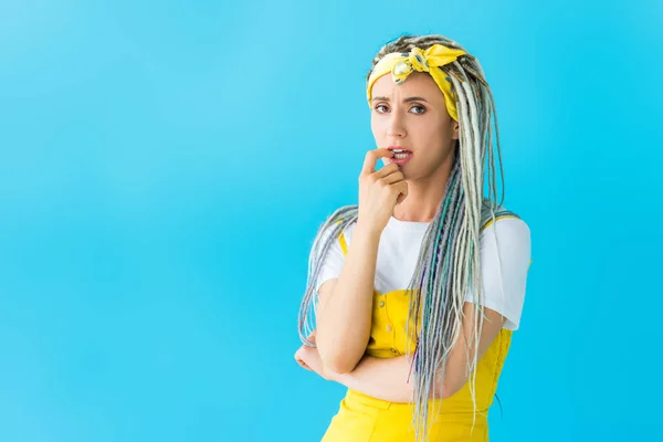 Worried girl with dreadlocks biting finger isolated on turquoise — Stock Photo