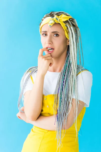 Chica preocupada con rastas mordiendo dedo aislado en turquesa — Stock Photo