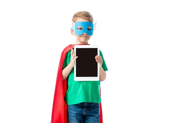 Smiling preschooler boy in mask and hero cloak holding digital tablet with blank screen isolated on white — Stock Photo