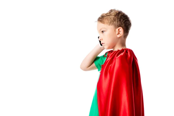 Side view of serious preschooler boy in red hero cloak talking on smartphone isolated on white — Stock Photo