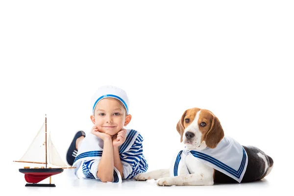 Enfant préscolaire souriant en costume marin avec bateau jouet et chien beagle sur blanc — Photo de stock