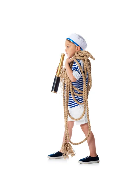 Full length view of preschooler child in sailor suit holding spyglass and rope isolated on white — Stock Photo