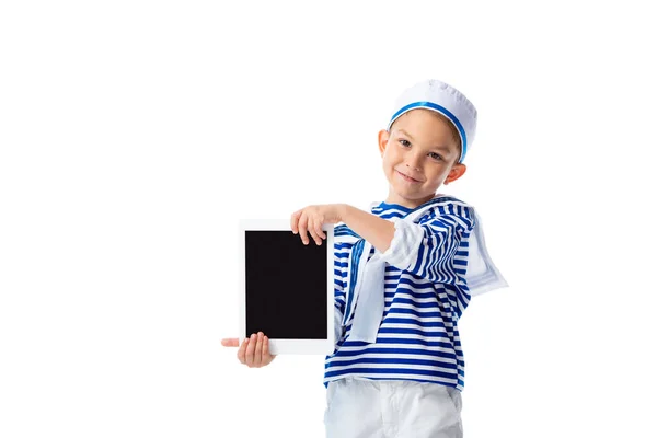Vista frontal del niño en edad preescolar sonriente en traje de marinero sosteniendo tableta digital con pantalla en blanco aislado en blanco - foto de stock
