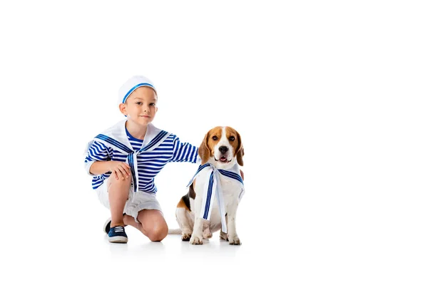 Smiling preschooler child in sailor costume and beagle dog on white — Stock Photo