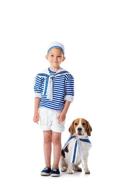 Vista completa del bambino in età prescolare sorridente in costume da marinaio e cane beagle su bianco — Foto stock