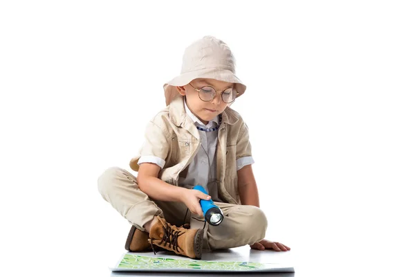 Explorateur enfant en chapeau et lunettes tenant lampe de poche et regardant la carte sur blanc — Photo de stock
