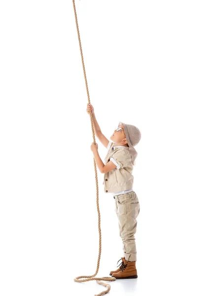 Full length view of focused explorer kid in hat and glasses holding rope isolated on white — Stock Photo