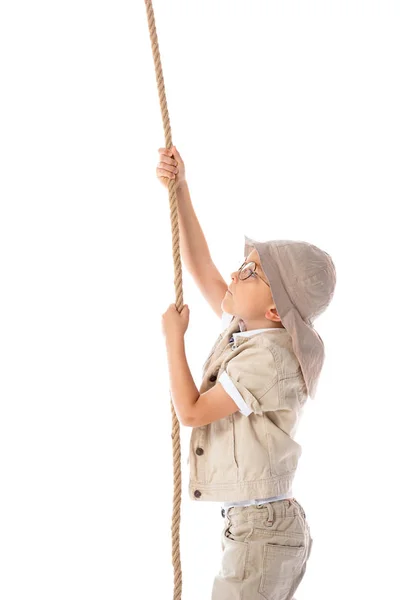 Vista laterale del bambino esploratore focalizzato in cappello e occhiali tenendo la corda isolata sul bianco — Foto stock