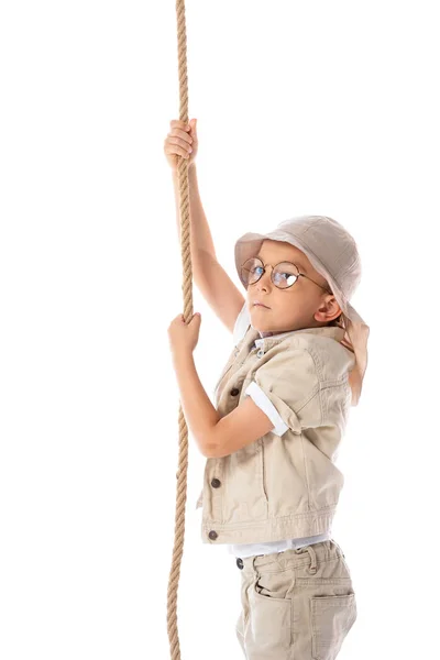 Niño explorador enfocado en sombrero y gafas con cuerda aislada en blanco - foto de stock