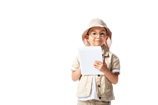 Vista frontal del niño explorador alegre en gafas y sombrero sosteniendo tableta digital aislada en blanco - foto de stock