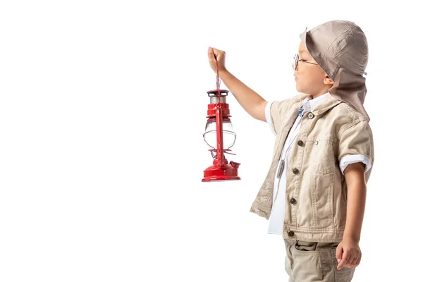 Side view of explorer boy in glasses and hat holding red lantern isolated on white — Stock Photo