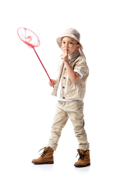 Full length view of explorer kid in hat holding butterfly and showing hush sign net isolated on white — Stock Photo