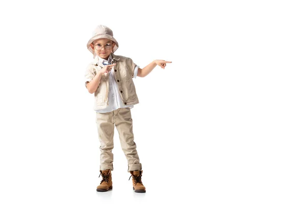 Full length view of smiling explorer boy in hat and glasses pointing with fingers isolated on white — Stock Photo