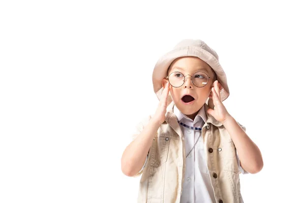Niño explorador sorprendido en sombrero y gafas mirando hacia otro lado con la boca abierta aislada en blanco - foto de stock