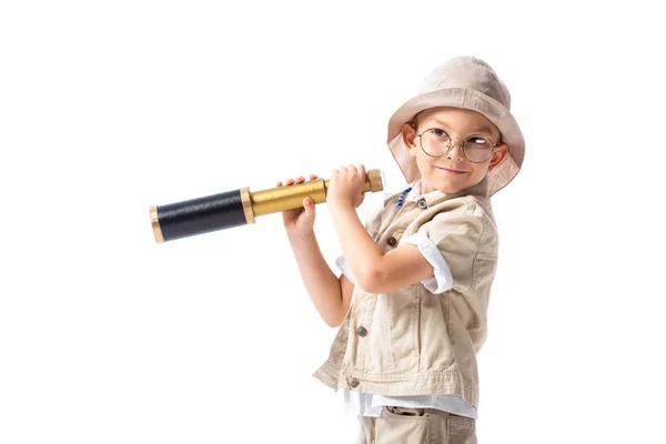 Menino explorador sorridente em óculos e chapéu segurando spyglass isolado em branco — Fotografia de Stock