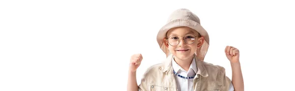 Plano panorámico de niño explorador sonriente en sombrero y gafas mirando a la cámara y mostrando sí gesto aislado en blanco - foto de stock